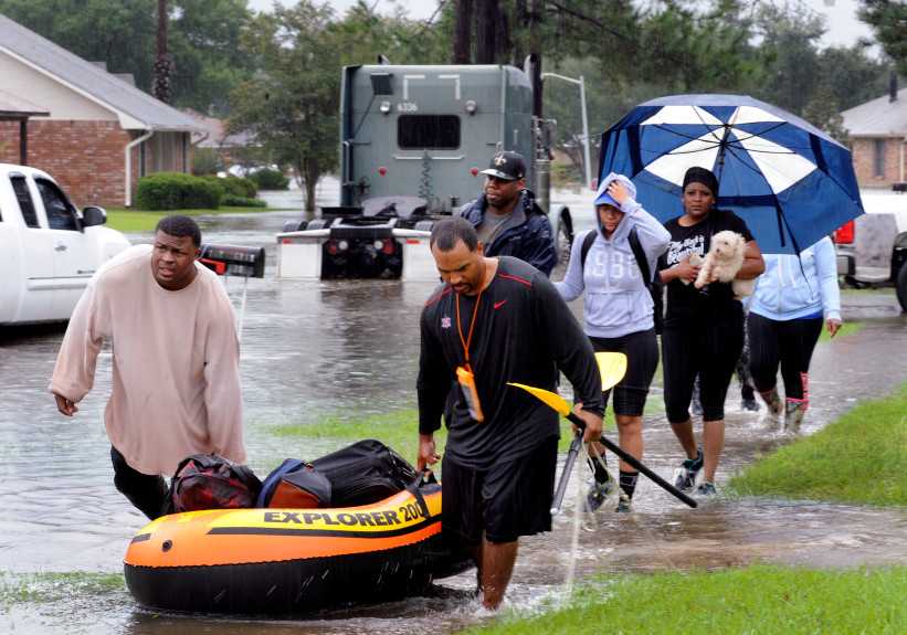Residents use a raft to evacuate as others walk out of their neighbor Saturday, Aug. 13, 2016, in Baton Rouge, La. Louisiana Gov. John Bel Edwards says more than 1,000 people in south Louisiana have been rescued from homes, vehicles and even clinging to trees as a slow-moving storm hammers the state with flooding. (John Oubre/The Advocate via AP)